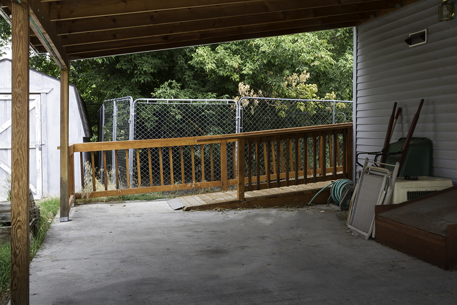 A zoomed in view of the back wooden ramp. A small metallic lip smooths the transition from the end of the ramp to the concrete driveway.